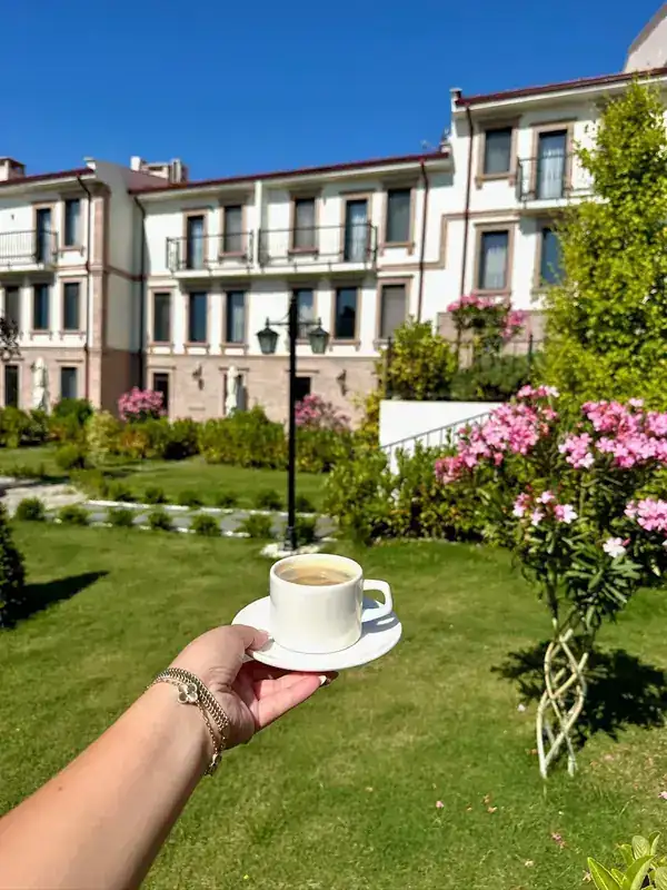 Bahçede bir fincan kahve, arkada otelin binası